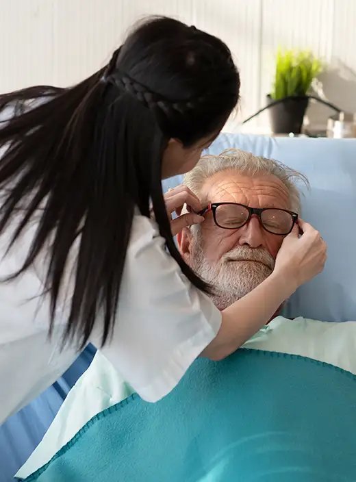 Pflegekraft hilft einem Bewohner im Pflegebett