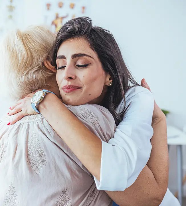 Pflegekraft umarmt eine ältere Bewohnerin